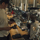 A barista working on commercial espresso machine. He is making a latte from an espresso shot. 